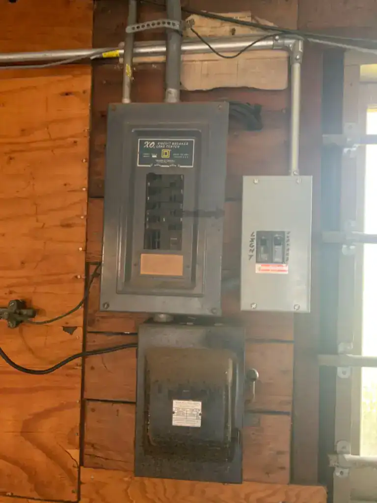 Vintage 100 amp load center with a dedicated range breaker, a small subpanel added later, and an older fused disconnect below