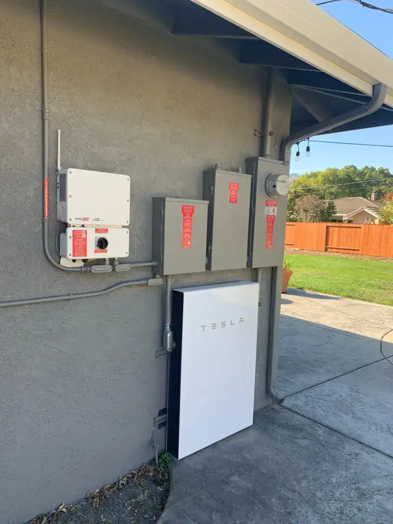 Solar inverter, disconnects, backup load center, main panel, PG&E meter and battery storage mounted on a home's exterior wall
