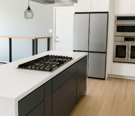 A striking contemporary kitchen featuring a bold black island and premium cooking appliances. Walnut Creek Contemporary kitchen remodel with black island cabinetry, white quartz waterfall countertops, built-in double ovens, and stainless steel hood.