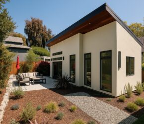 A custom detached ADU in Oakland featuring modern architecture, energy-efficient design, covered outdoor living space, and low-maintenance landscaping. Modern Oakland ADU exterior featuring white stucco siding, black-framed windows, a covered patio, drought-tolerant landscaping, and contemporary shed roof architecture.