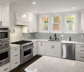 Classic shaker cabinetry paired with quartz countertops creates a timeless kitchen design. San Francisco White shaker kitchen remodel with quartz countertops, custom range hood, stainless steel appliances, and large center island.