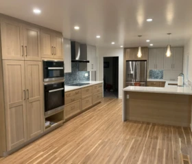 Natural wood finishes and contemporary details create a warm, welcoming kitchen. Lafayette Open-concept kitchen with natural wood cabinets, large island, quartz countertops, hardwood floors, and modern pendant lighting.