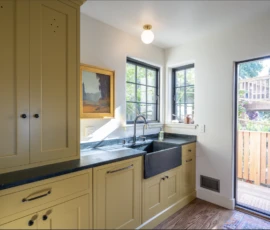 Kitchen remodel in Berkeley, with yellow cabinetry and a black farmhouse sink. Custom kitchen remodel-Berkeley, with yellow cabinets, dark countertops, and a black farmhouse sink.