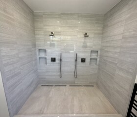 Two full stations, each with its own valve, niches, and drain. Large double shower in Mill Valley, Marin county, with two rain heads, twin linear drains, and gray porcelain tile