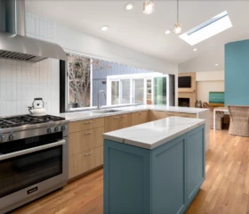 Natural materials and abundant daylight define this custom Alamo kitchen. Modern kitchen in Alamo featuring oak cabinetry, blue island, quartz countertops, and large picture window.