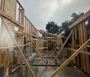Roof truss installation. Structural wood wall framing with temporary bracing during a home addition.