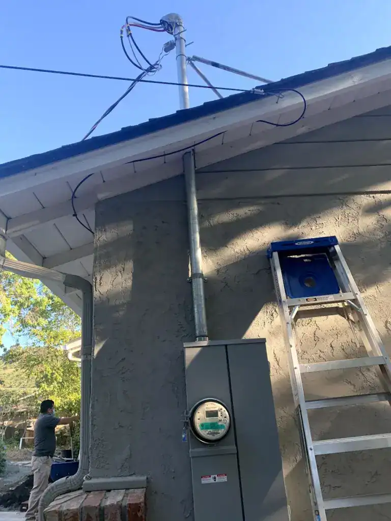 New galvanized service mast and weatherhead through the roof eave feeding a new meter and main service enclosure