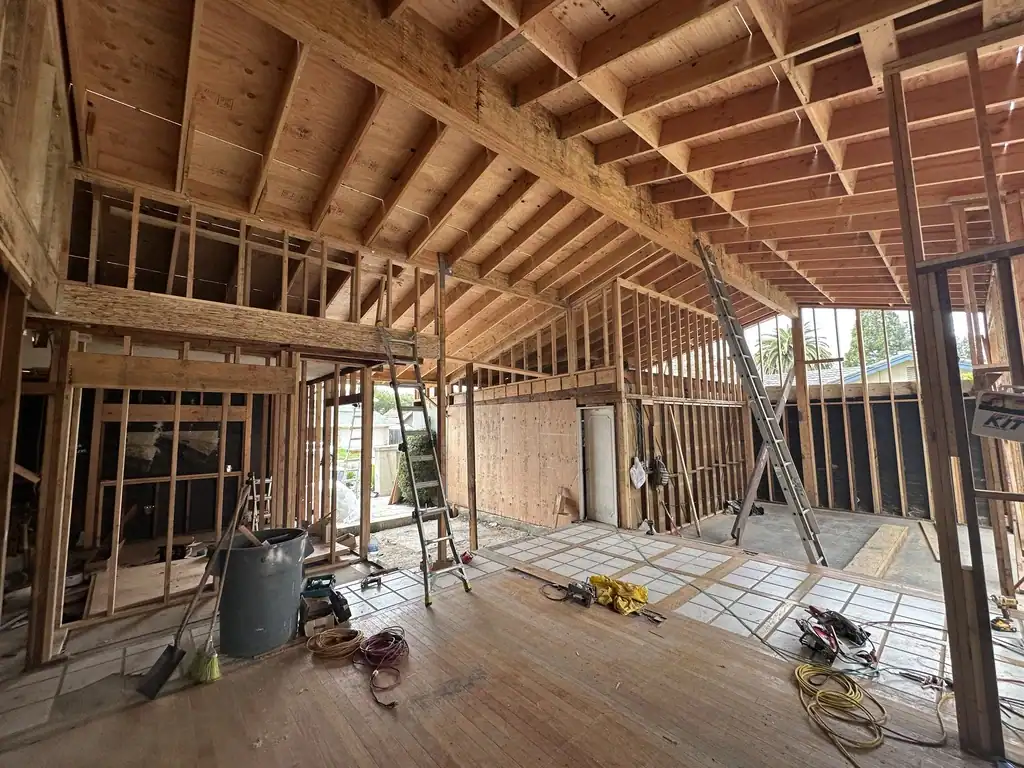 Home stripped to the studs during a major renovation, showing new structural framing and the exposed electrical panel