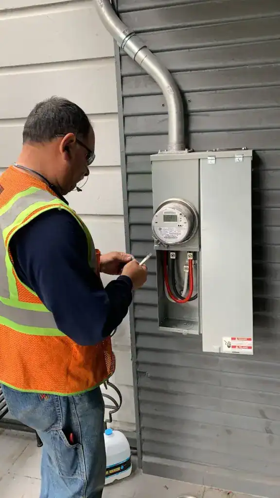 Utility technician at a newly installed meter and main service enclosure with the service conductors landed